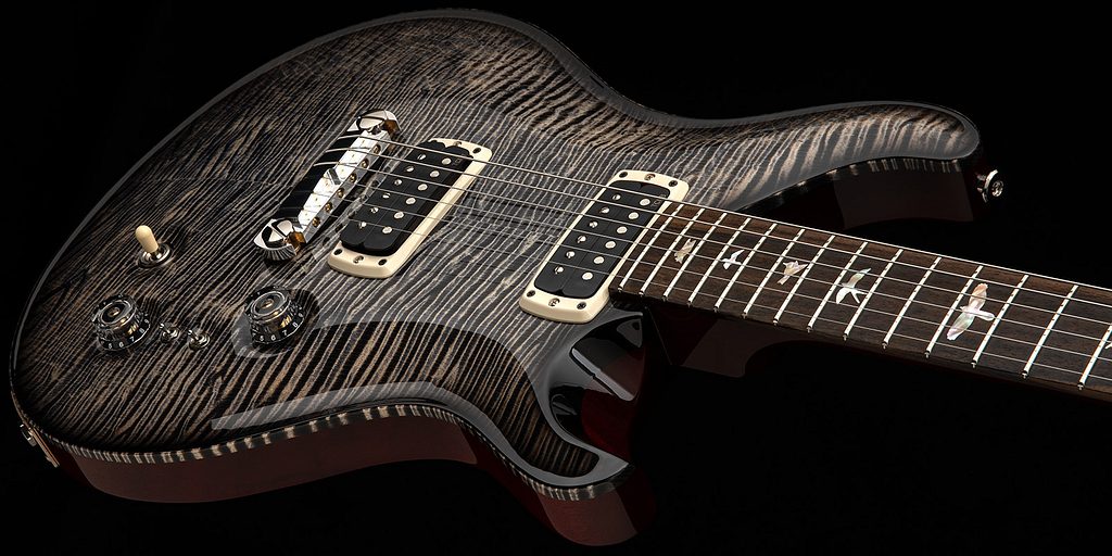 Close-up of a PRS electric guitar with a highly figured maple top in a charcoal finish, dual humbucker pickups, bird inlays on the fretboard, and premium hardware against a dark background.