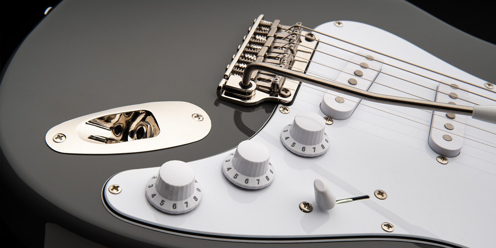 Close-up of the PRS SE Silver Sky electric guitar in a metallic finish, highlighting its white pickguard, synchronized tremolo bridge, control knobs, and input jack plate. The vintage-style tremolo arm and single-coil pickups add to its classic design.